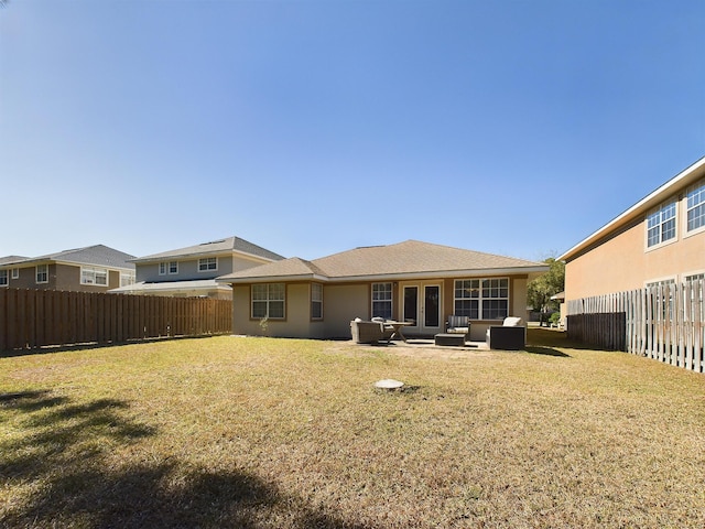 back of house featuring french doors, a patio, a fenced backyard, a yard, and stucco siding