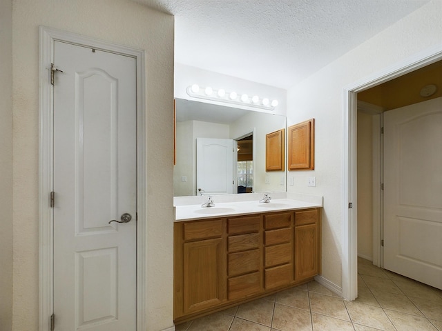 bathroom featuring double vanity, a sink, a textured ceiling, and tile patterned floors