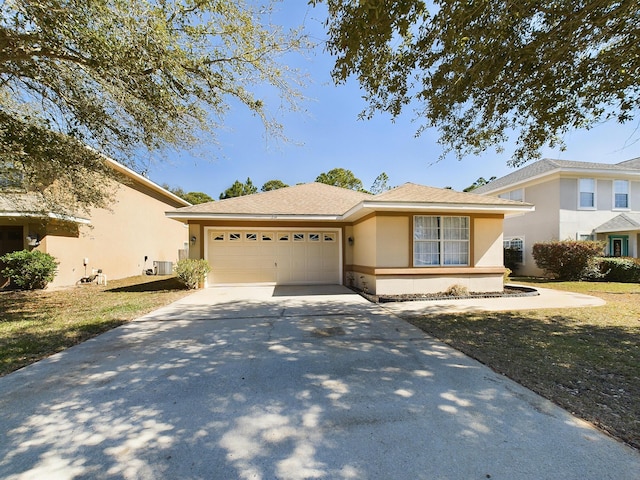 view of front of property with concrete driveway, central AC unit, an attached garage, and stucco siding