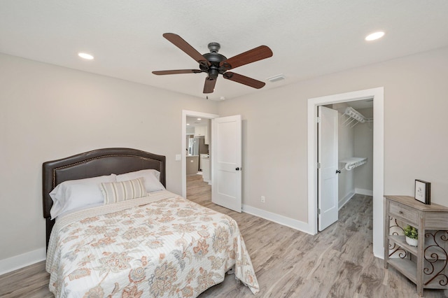 bedroom with ceiling fan, a spacious closet, and light hardwood / wood-style floors