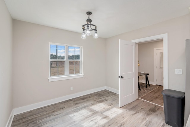 spare room with a notable chandelier and light hardwood / wood-style flooring