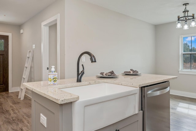 kitchen with sink, decorative light fixtures, light wood-type flooring, stainless steel dishwasher, and an island with sink