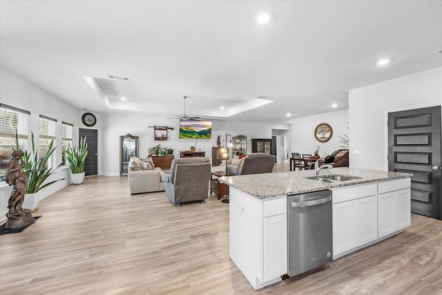 kitchen featuring a kitchen island with sink, a tray ceiling, dishwasher, and white cabinets