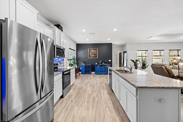 kitchen featuring sink, appliances with stainless steel finishes, a kitchen island with sink, light hardwood / wood-style floors, and white cabinets