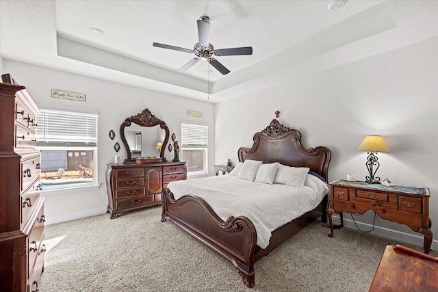 carpeted bedroom featuring ceiling fan and a raised ceiling