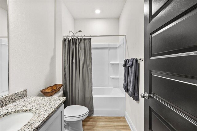 full bathroom featuring hardwood / wood-style flooring, vanity, toilet, and shower / tub combo