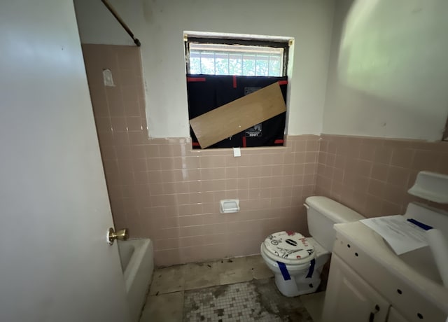 bathroom featuring vanity, toilet, a bath, and tile walls