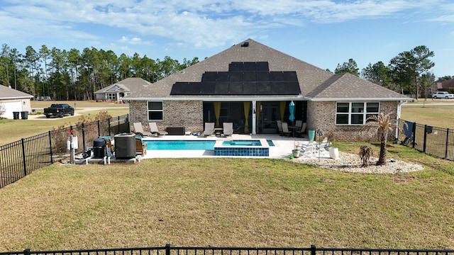 back of property with a swimming pool with hot tub, a yard, solar panels, and a patio area