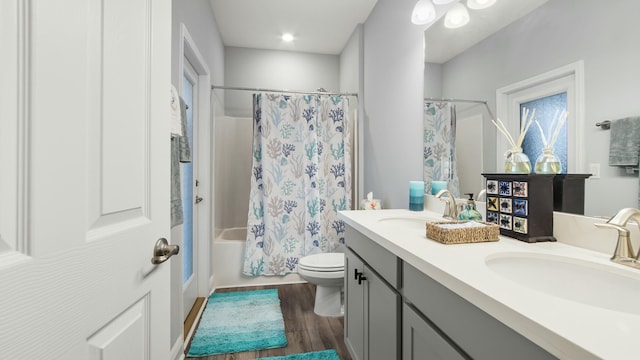 full bathroom featuring hardwood / wood-style flooring, vanity, toilet, and shower / tub combo