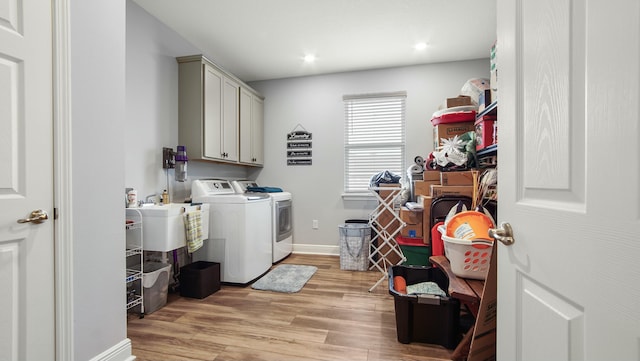 clothes washing area featuring cabinets, sink, separate washer and dryer, and light wood-type flooring