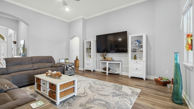 living room with hardwood / wood-style flooring, ceiling fan, a high ceiling, and crown molding