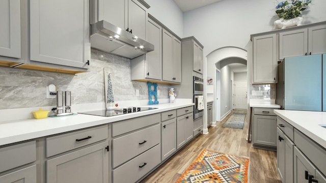 kitchen with black electric stovetop, refrigerator, gray cabinetry, and light hardwood / wood-style floors