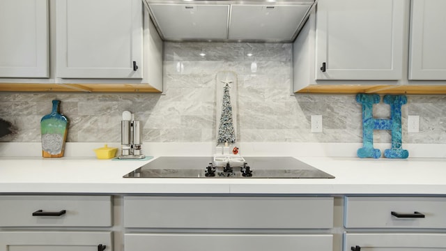 kitchen with gray cabinets, black electric cooktop, decorative backsplash, and range hood