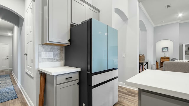 kitchen with fridge, gray cabinetry, backsplash, and light hardwood / wood-style floors