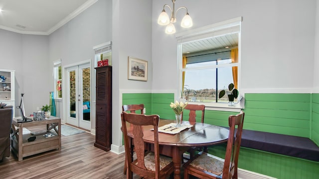 dining space featuring french doors, crown molding, a chandelier, and wood-type flooring