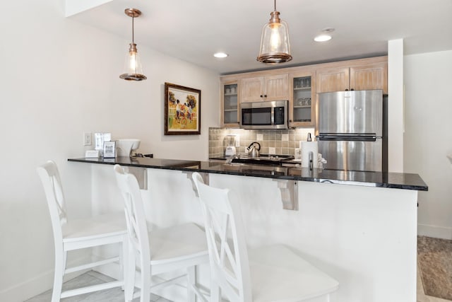 kitchen with appliances with stainless steel finishes, kitchen peninsula, and decorative light fixtures