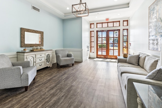 living room with a notable chandelier, a tray ceiling, wood-type flooring, and french doors