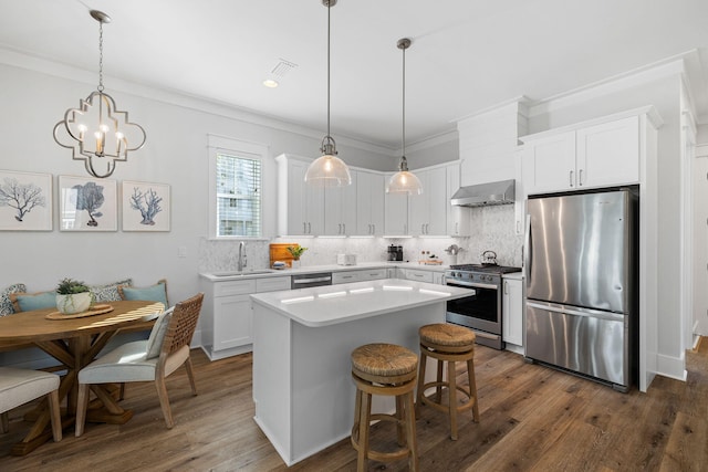 83 Sawgrass Ln, Santa Rosa Beach, FL 32459 - kitchen featuring pendant lighting, wall chimney range hood, appliances with stainless steel finishes, white cabinets, and a kitchen island
