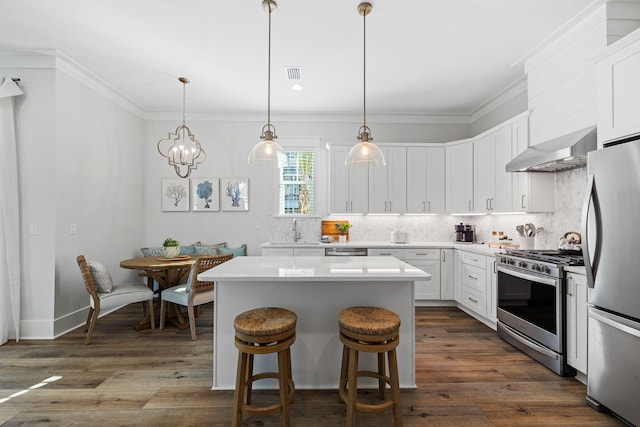 83 Sawgrass Ln, Santa Rosa Beach, FL 32459 - kitchen featuring decorative light fixtures, a center island, wall chimney range hood, stainless steel appliances, and white cabinets