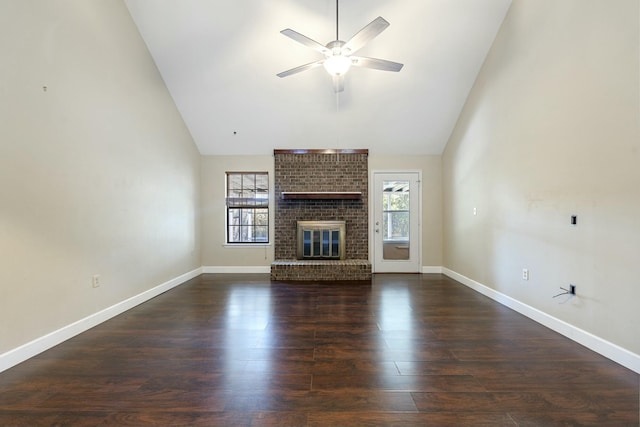 unfurnished living room featuring a healthy amount of sunlight, a fireplace, high vaulted ceiling, and dark wood-type flooring