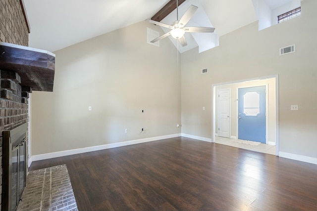 unfurnished living room with a brick fireplace, visible vents, a ceiling fan, and wood finished floors