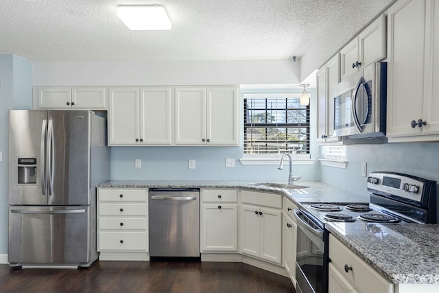 kitchen with white cabinets, dark wood-style floors, stainless steel appliances, and a sink