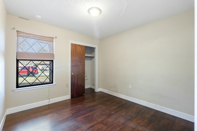 unfurnished bedroom featuring a textured ceiling, a closet, baseboards, and dark wood-style flooring