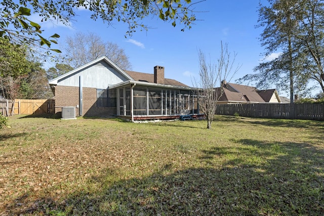 back of house with a sunroom, a fenced backyard, a yard, and a chimney