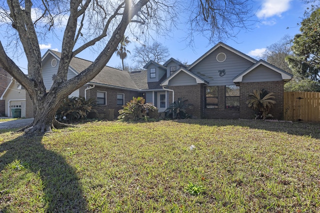 view of front of house featuring brick siding, a front lawn, and fence