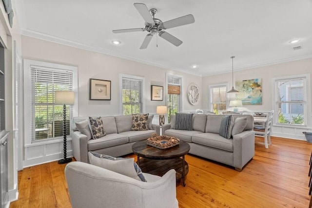 living room with ornamental molding, a wealth of natural light, ceiling fan, and light wood-type flooring