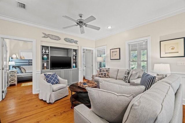 living room with crown molding, wood-type flooring, built in features, and ceiling fan