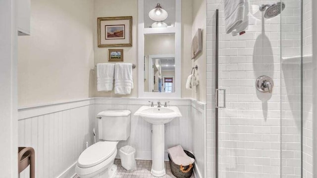 bathroom with a shower with door, sink, and toilet