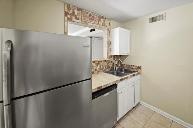 kitchen with visible vents, white cabinets, a sink, stainless steel appliances, and backsplash