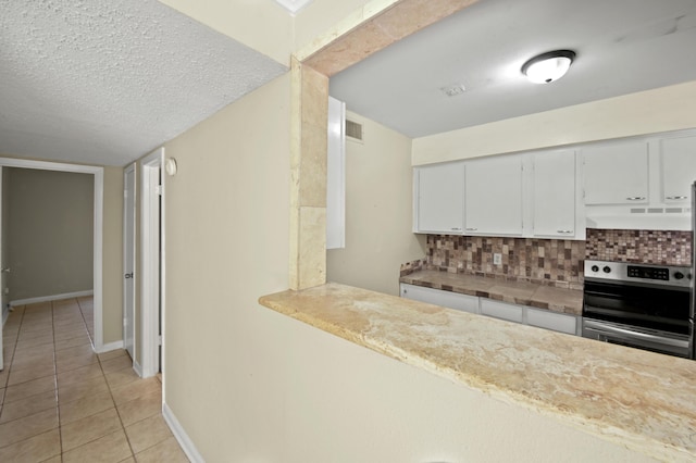 kitchen with tasteful backsplash, visible vents, stainless steel range with electric cooktop, and under cabinet range hood