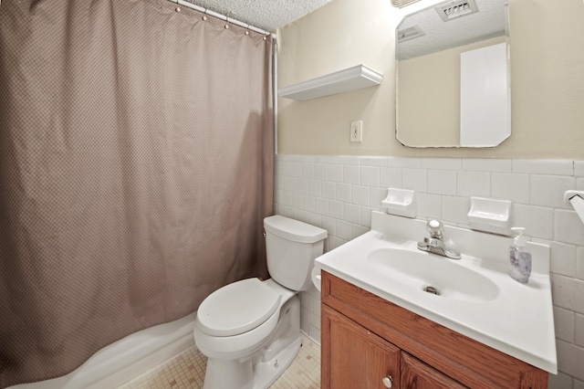 bathroom with tile walls, visible vents, wainscoting, a textured ceiling, and vanity