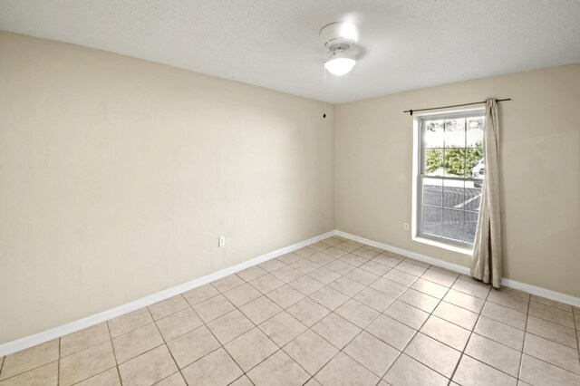 spare room with light tile patterned flooring, a textured ceiling, and baseboards