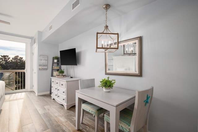 dining space with an inviting chandelier, a wall of windows, and light hardwood / wood-style flooring