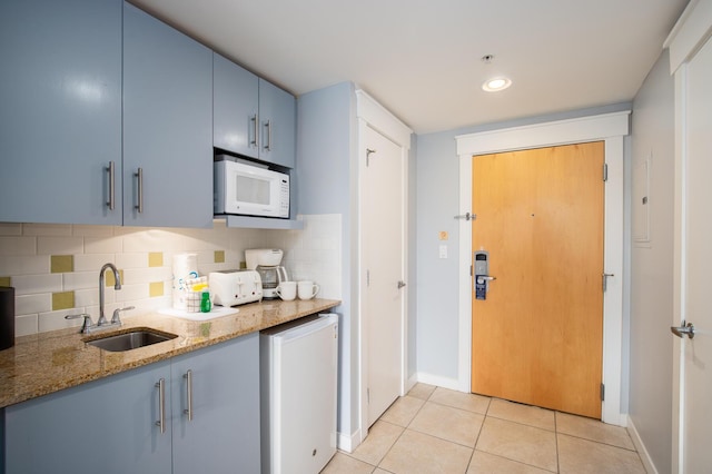 kitchen featuring tasteful backsplash, sink, light tile patterned floors, and light stone countertops