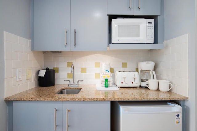 kitchen featuring light stone counters, sink, and decorative backsplash