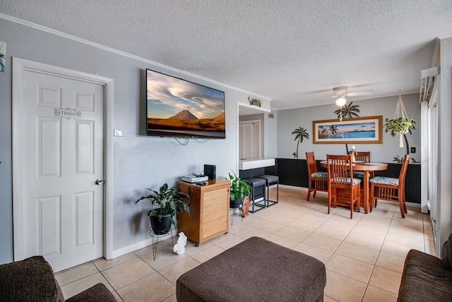 tiled living room featuring ceiling fan, ornamental molding, and a textured ceiling