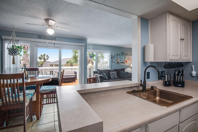 kitchen featuring sink, light tile patterned floors, ceiling fan, white cabinetry, and a textured ceiling