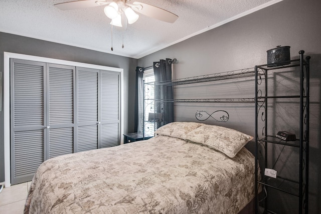 bedroom featuring light tile patterned floors, ceiling fan, ornamental molding, a textured ceiling, and a closet