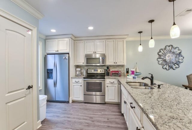 kitchen featuring sink, crown molding, decorative light fixtures, appliances with stainless steel finishes, and backsplash