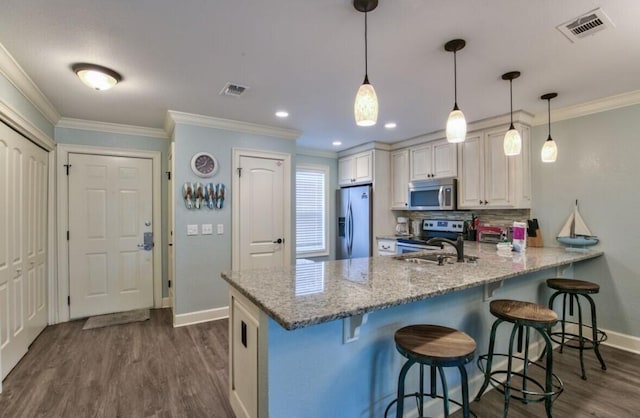 kitchen with hanging light fixtures, appliances with stainless steel finishes, a kitchen breakfast bar, kitchen peninsula, and light stone countertops