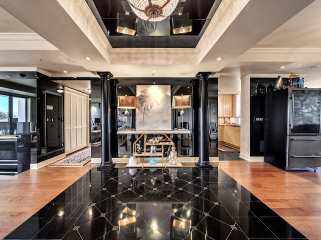 interior space featuring crown molding, stainless steel fridge, a raised ceiling, and ornate columns