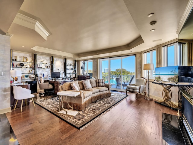 living room featuring a tray ceiling, wood-type flooring, and ornamental molding