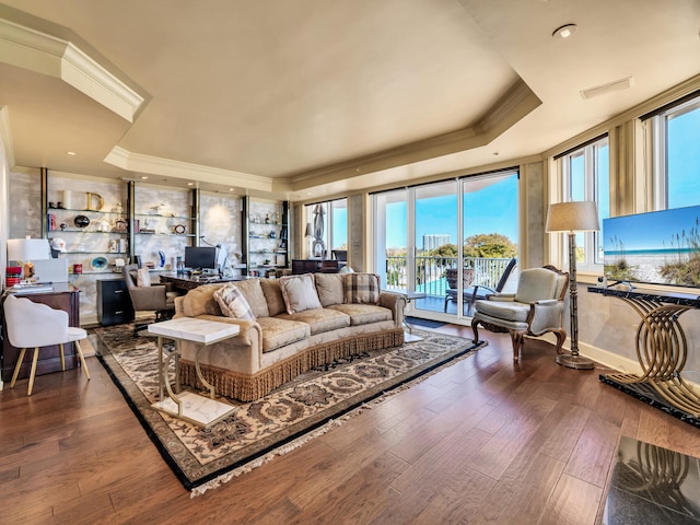 living room featuring hardwood / wood-style flooring, ornamental molding, and a tray ceiling