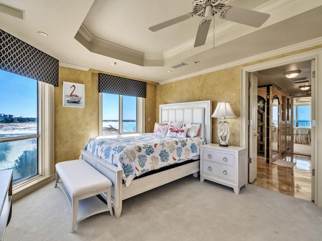 carpeted bedroom featuring a raised ceiling, crown molding, and ceiling fan