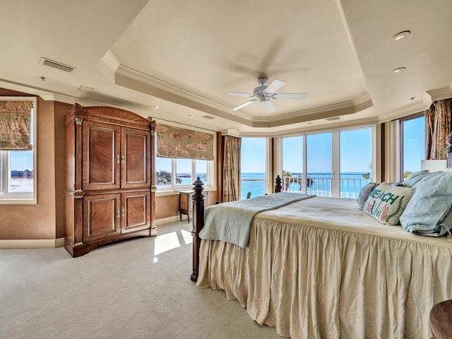 carpeted bedroom with crown molding, a water view, ceiling fan, and a tray ceiling