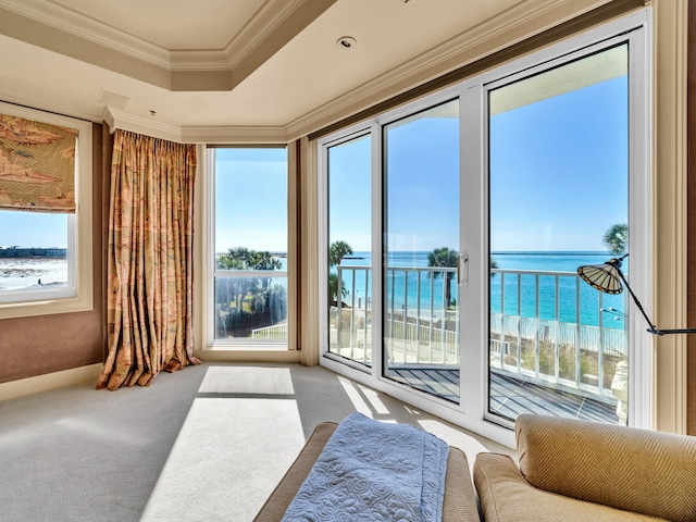 interior space with a water view, a beach view, and a tray ceiling